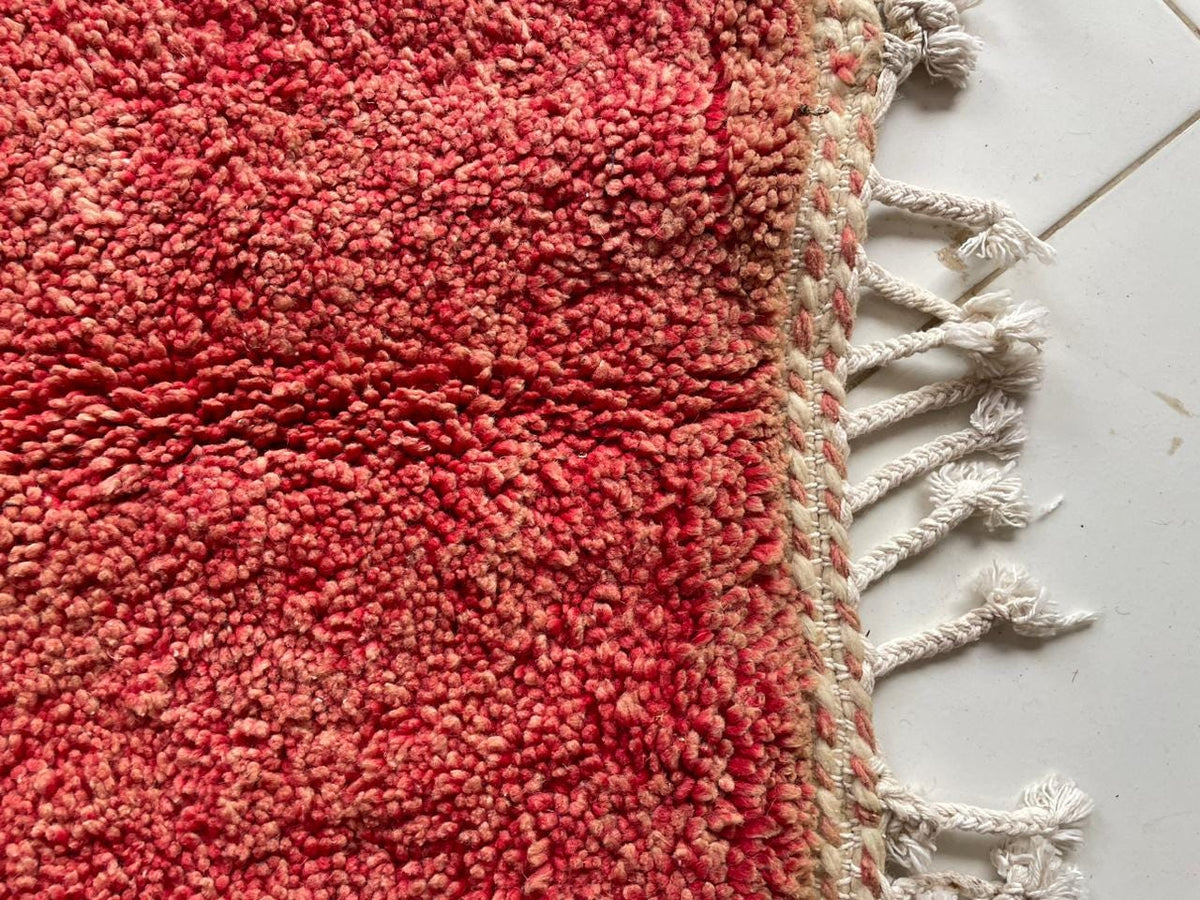 Detail shot of a red Moroccan rug featuring fringe detail.