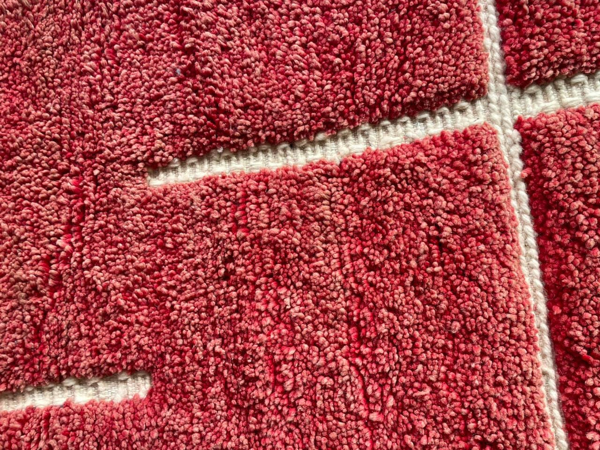 Detail view of a red Moroccan rug emphasizing its textured pattern.