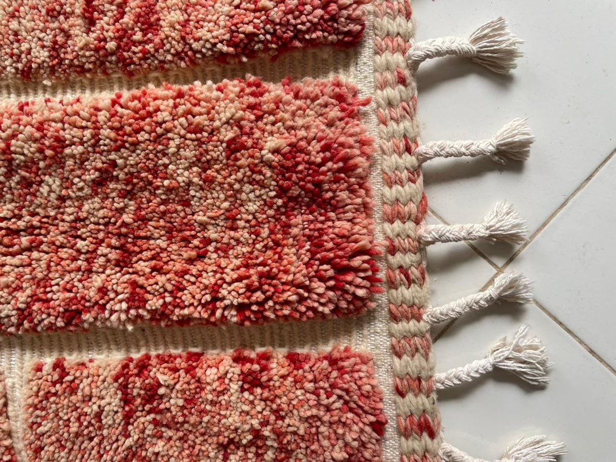 Detail view of a red Moroccan rug highlighting its textured surface and geometric pattern.