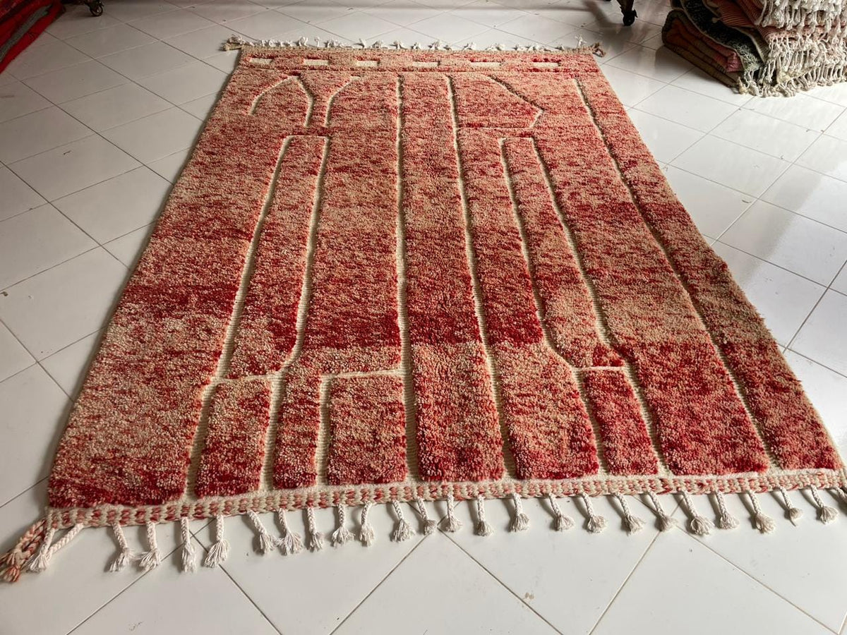 Detail view showcasing the fringe edges of a red Moroccan rug on a white background.