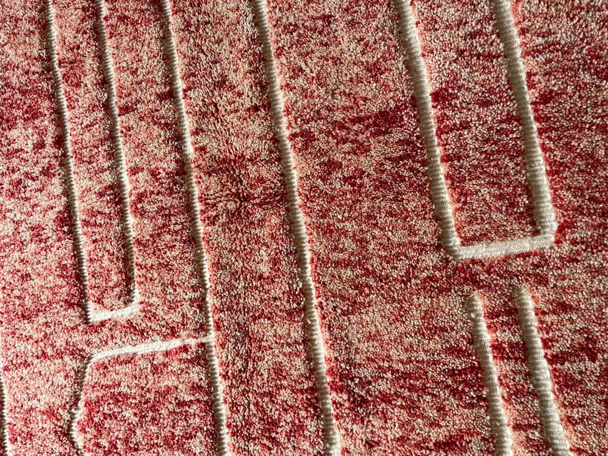 Detail view of a red Moroccan rug featuring geometric patterns on a contrasting background.