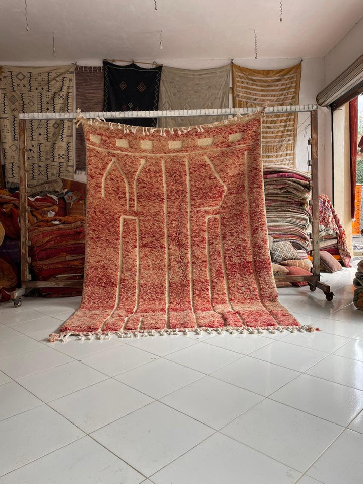 Lifestyle shot of a red Moroccan rug with geometric patterns on a natural background.