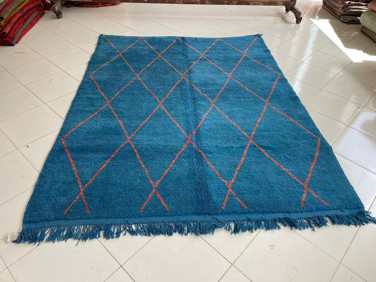 Top view of a turquoise Moroccan rug featuring fringe edges and geometric design.