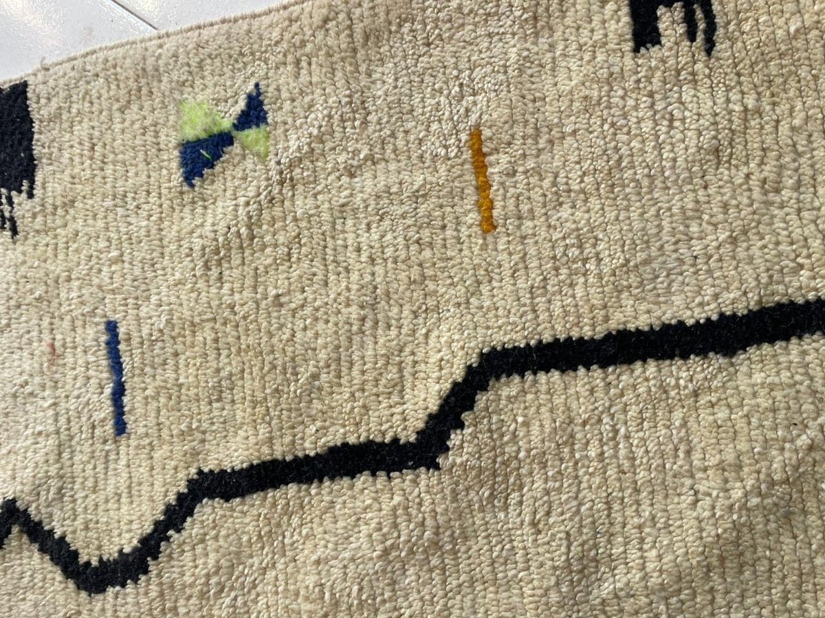 Detail shot of a white Moroccan rug with geometric patterns and a textured appearance.