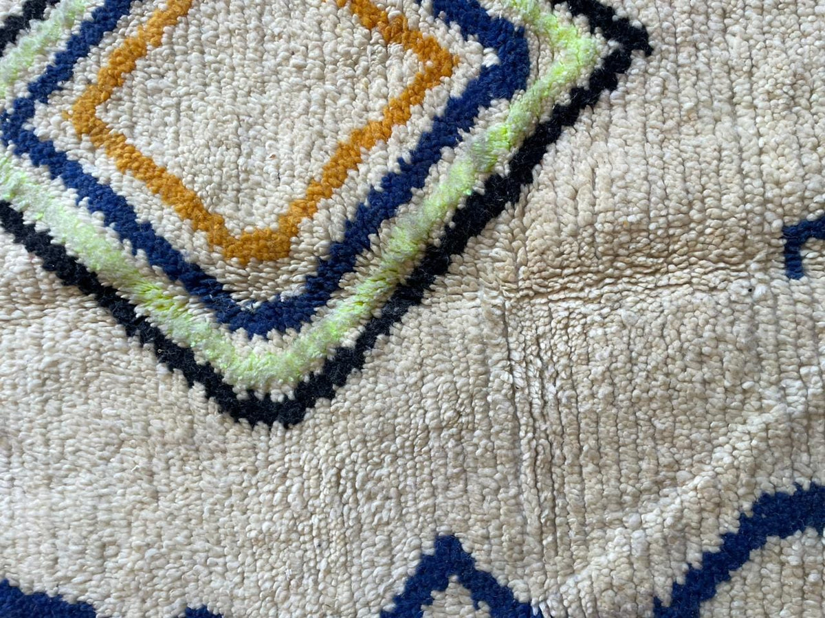 Detail shot of a white Moroccan rug featuring geometric patterns and a textured appearance.