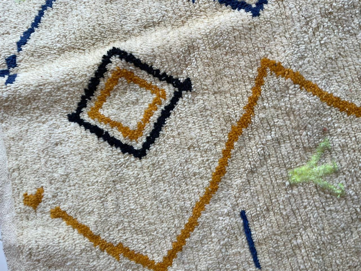 Detail shot of a white Moroccan rug with geometric patterns and a textured appearance.