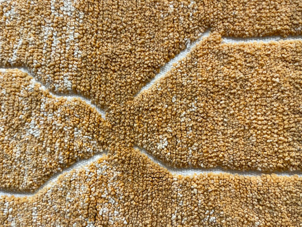 Close-up of a yellow rug with a geometric pattern and textured surface.