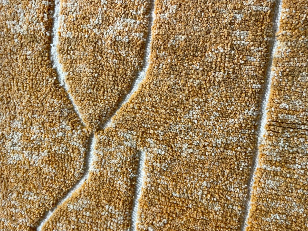 Close-up detail of a yellow Moroccan rug showing its textured surface and fringed edges.