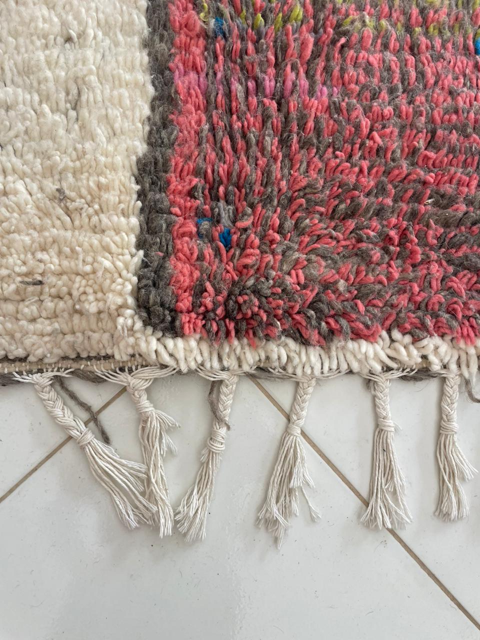 Detail shot of the corner of a colorful Moroccan rug showing fringe detail and vibrant patterns.