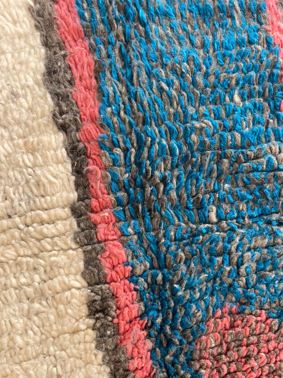 Close-up detail of a colorful Moroccan rug featuring a textured pattern and fringe edges.