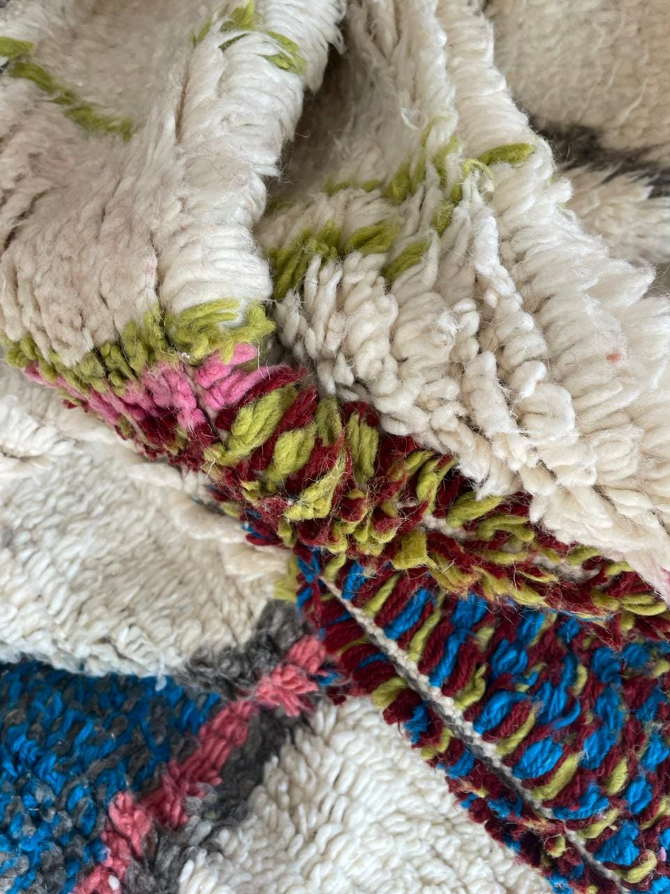 Detail shot of layered textures on a colorful Moroccan rug with vibrant colors.
