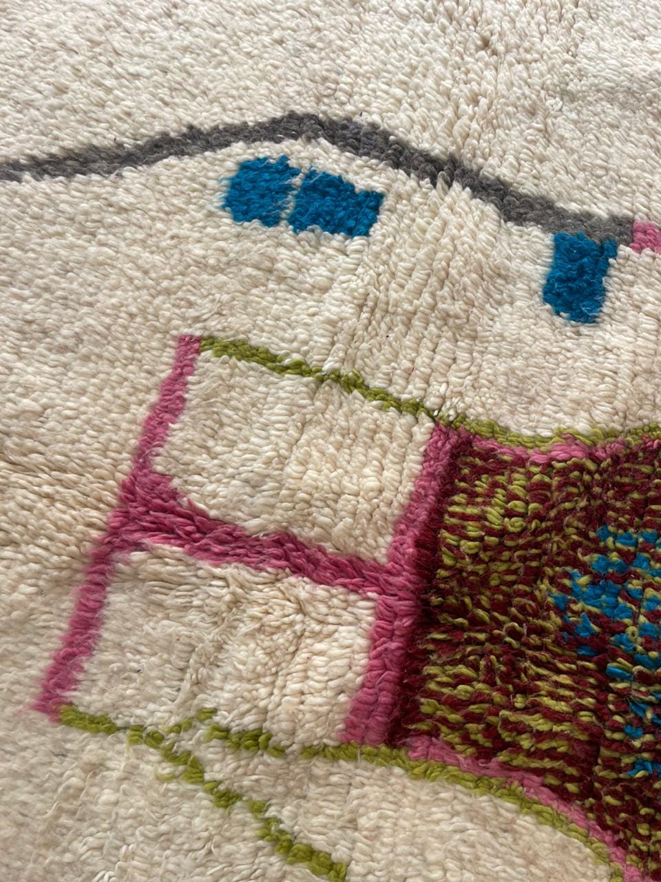 Close-up detail of a colorful Moroccan rug with geometric patterns and fringe edges.