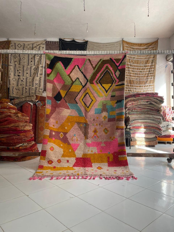 Lifestyle shot of a colorful Moroccan rug with geometric patterns in pink, yellow, and brown.