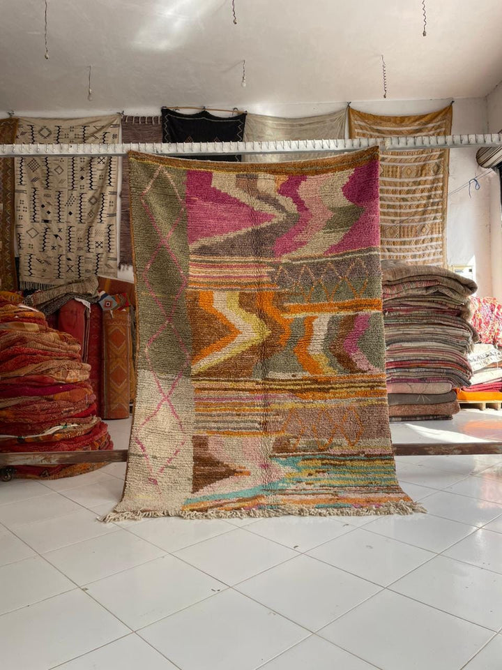 Lifestyle shot of a colorful Moroccan rug featuring pink, orange, and green tones.