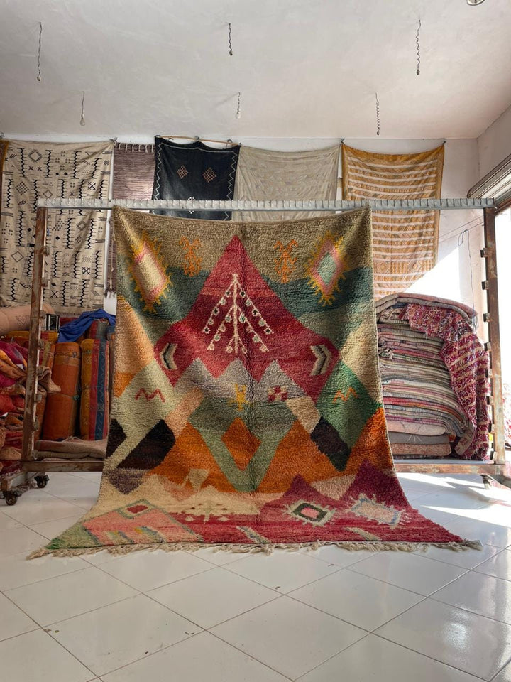 Lifestyle shot of colorful Moroccan rug featuring geometric patterns in red, green, orange, and blue.
