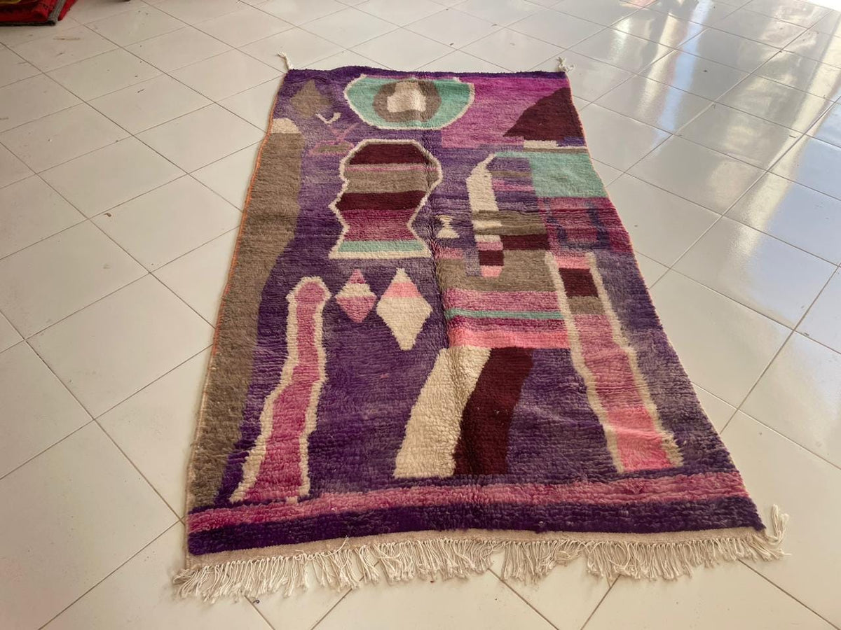 Close-up detail of a purple Moroccan rug featuring fringed edges and tribal patterns.
