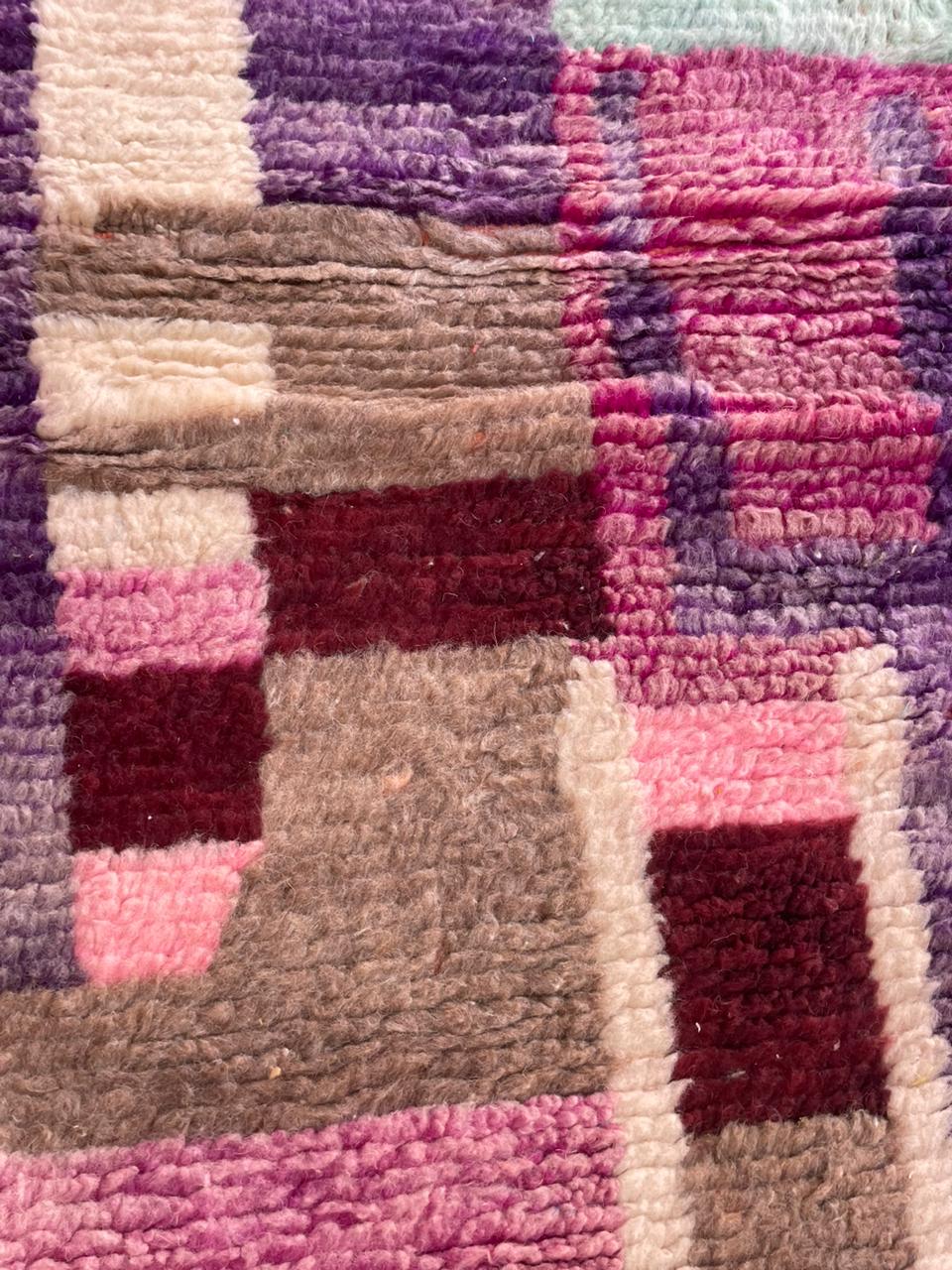 Close-up of a hand-woven purple rug displaying tribal patterns and a soft texture.