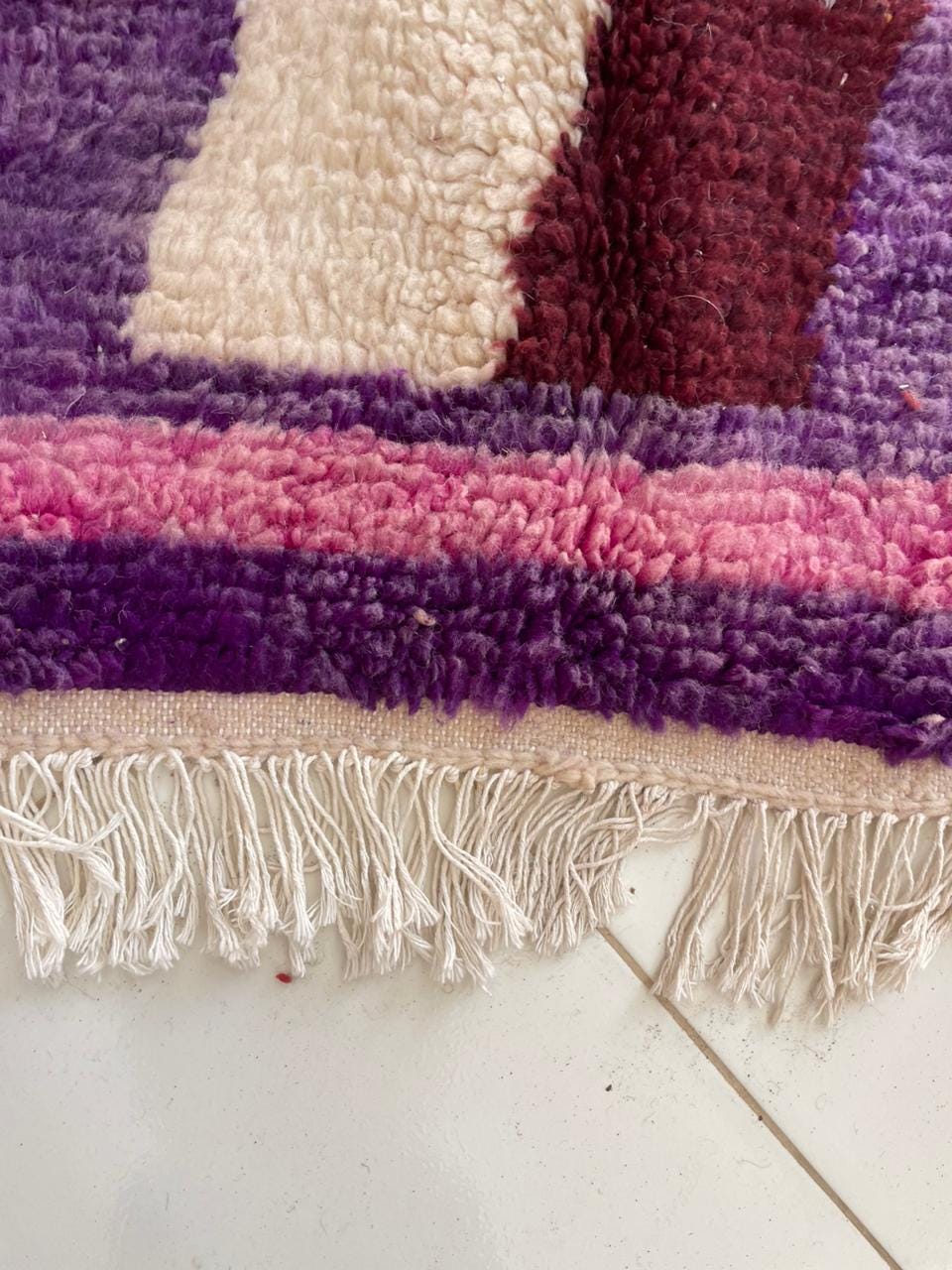 Close-up of a purple rug with colorful stripes and a textured surface.