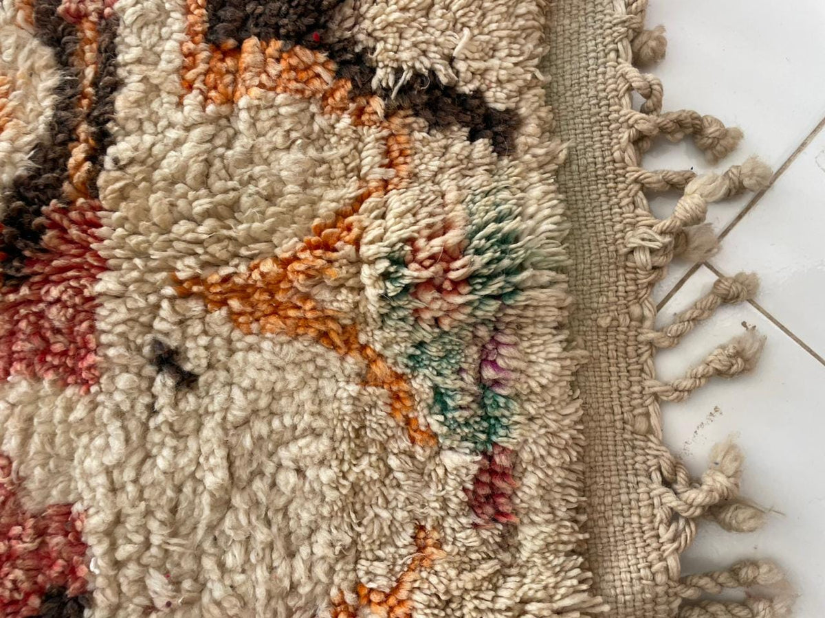 Close-up view of a handmade vintage Moroccan rug with fringe edges and tribal patterns.
