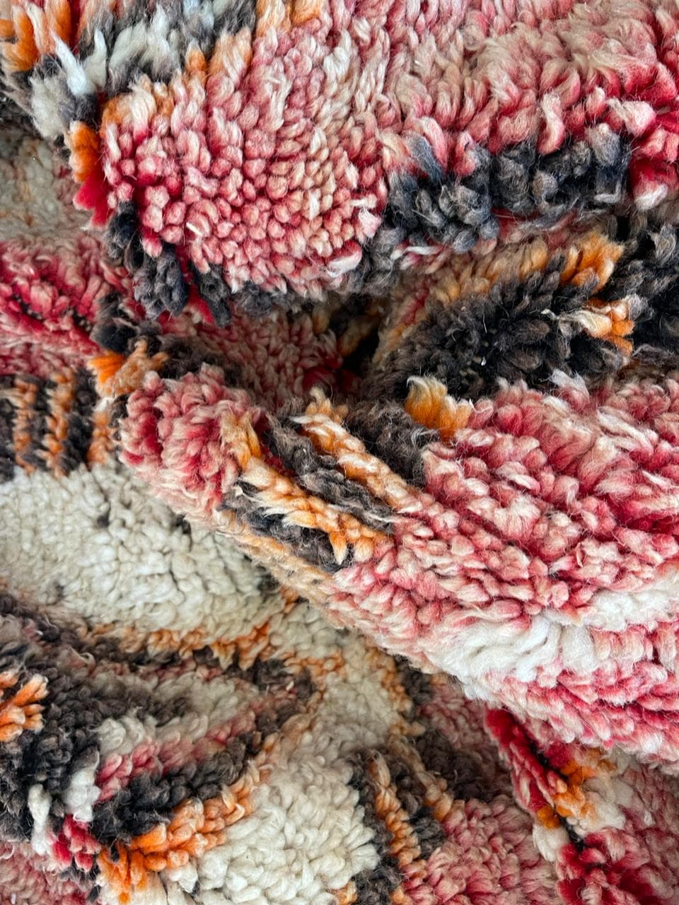 Detail shot of a vintage Moroccan rug featuring a tribal pattern in brown, red, and black.