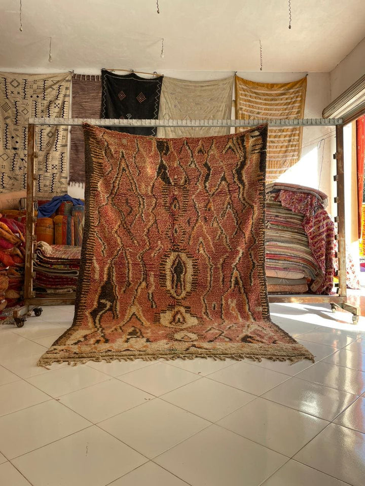 Lifestyle shot of a vintage Moroccan rug featuring brown and red tribal patterns.