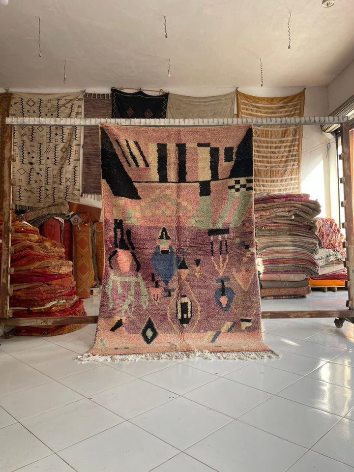 Lifestyle shot of a colorful Moroccan rug with pink, blue, and black patterns.