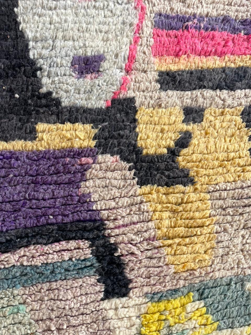 Close-up showing the textured surface and fringe edges of the colorful Moroccan rug.