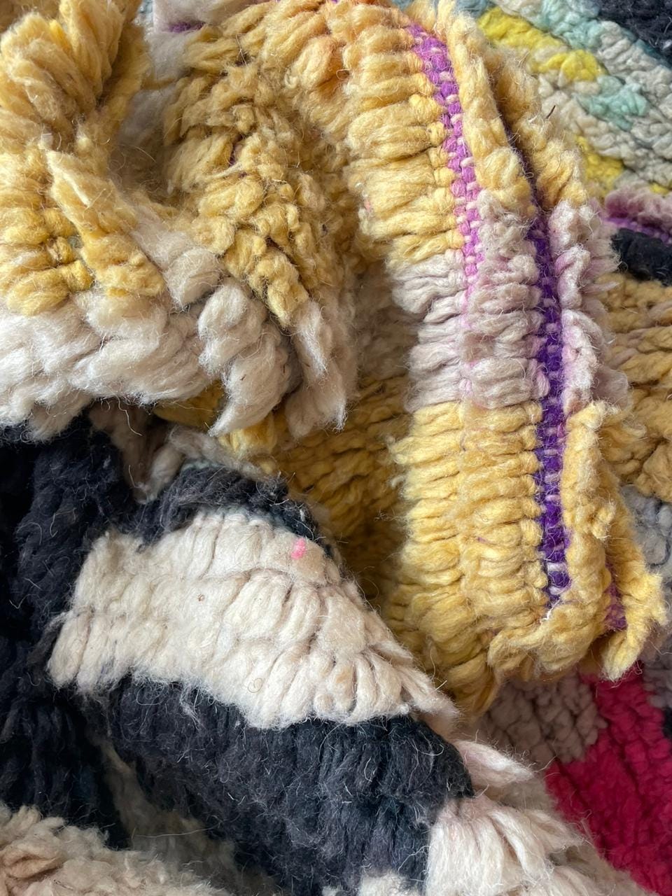 Close-up of the woven texture and colorful threads of the rug in purple and gray.