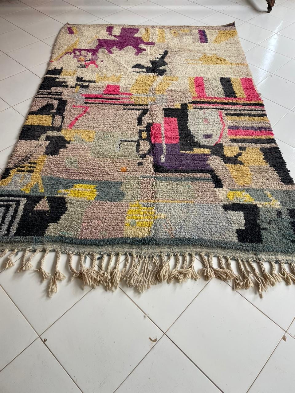 Lifestyle view of a colorful rug with fringe edges and abstract design on a natural background.