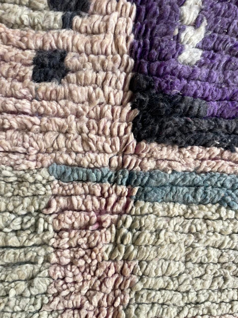 Detail close-up of colorful rug fibers in yellow, black, and purple.