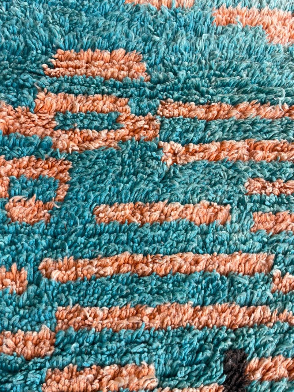 Detail of a textured rug with a thick pile in brown and red.