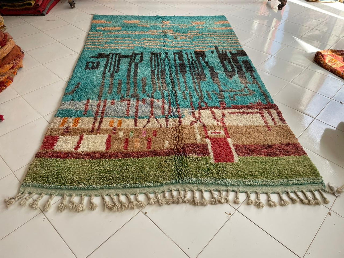 Top view of a colorful Moroccan rug featuring fringed edges in blue, red, cream, and green.