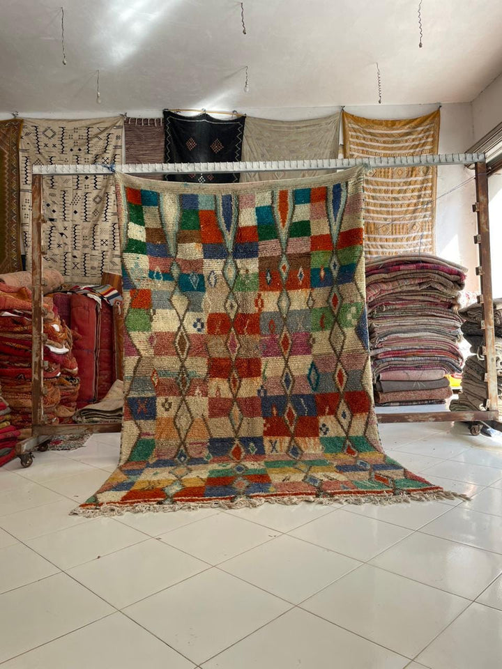 Lifestyle shot of a colorful Moroccan rug with red, blue, and green patterns in a natural setting.