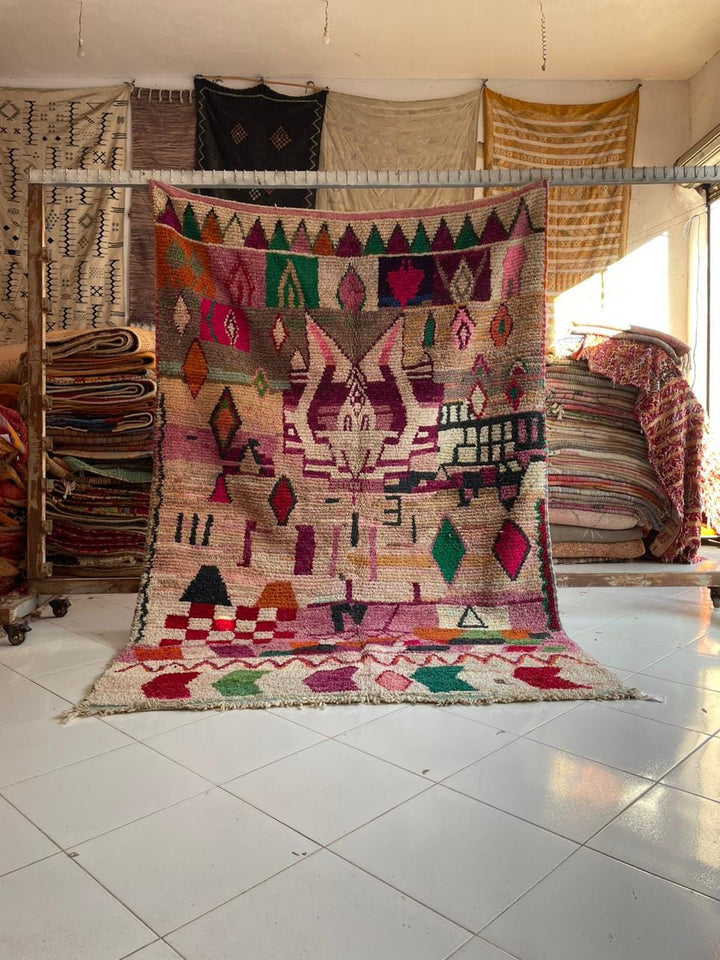 Lifestyle shot of a colorful pink Moroccan rug with geometric patterns in a natural setting.