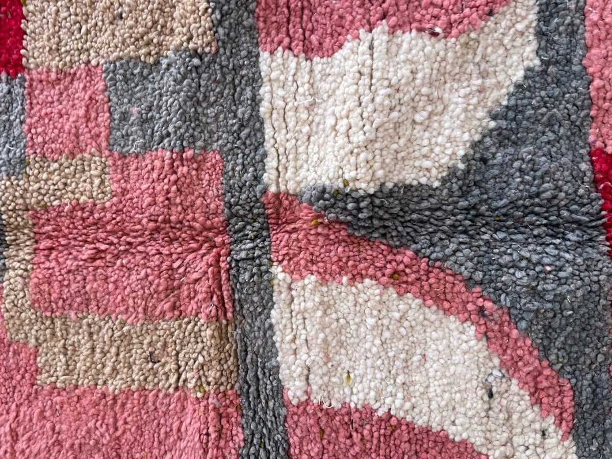 Close-up detail of a textured pattern on the pink Moroccan rug with tribal design.