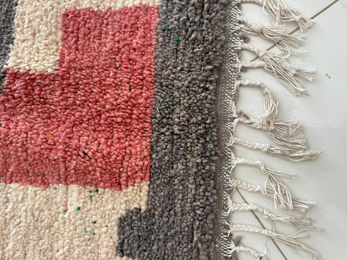 Close-up detail of fringe and textured pattern on the pink Moroccan rug.