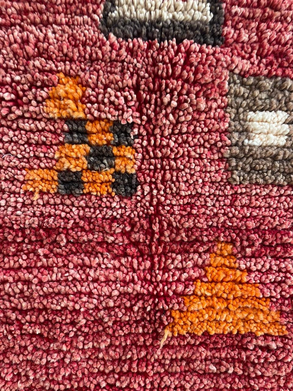 Close-up of geometric patterns in red and black on the vintage Moroccan rug.