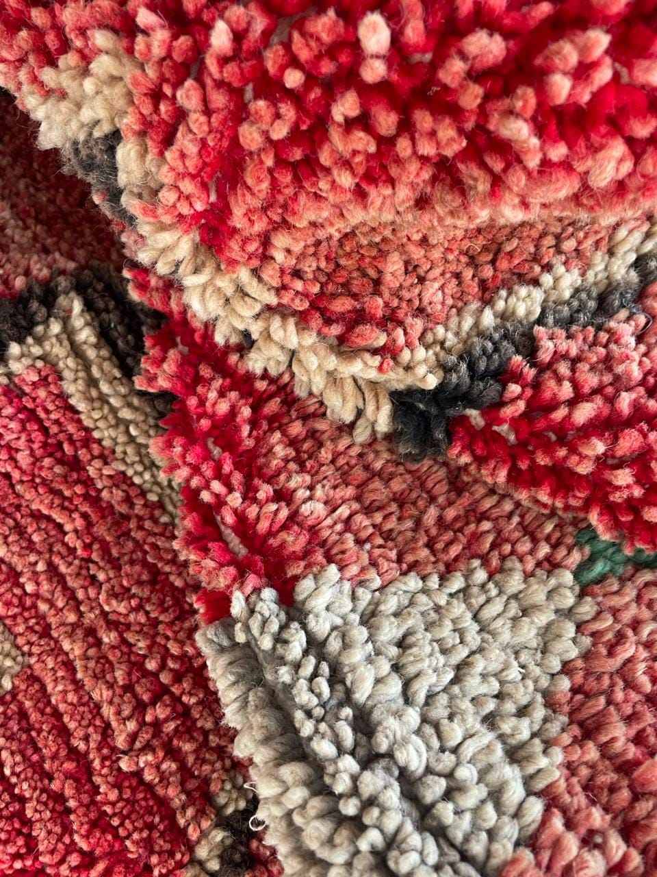 Close-up of a red Moroccan rug with a textured pattern in red, beige, and black.