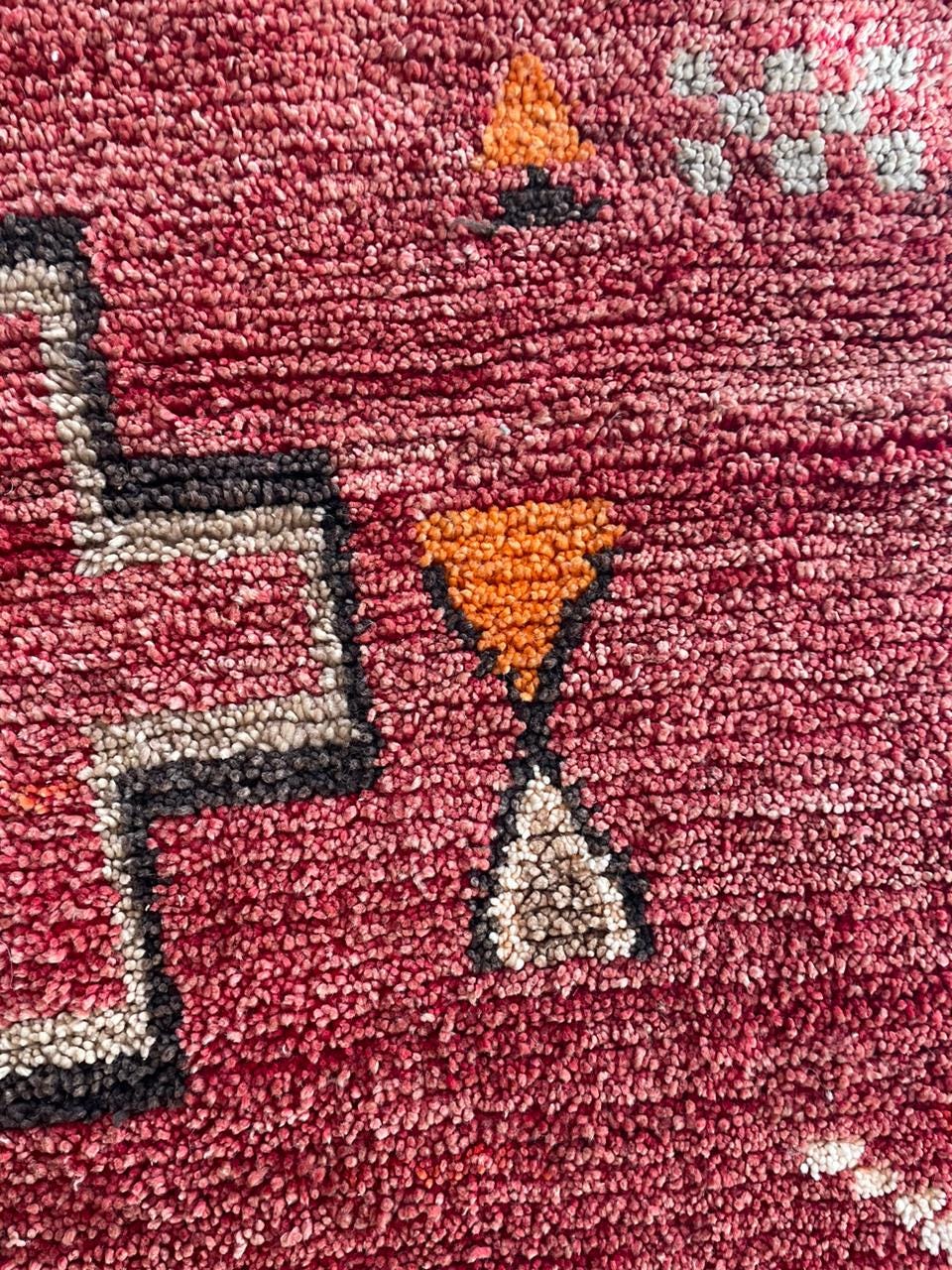 Close-up of geometric patterns in red and black on the vintage Moroccan rug.
