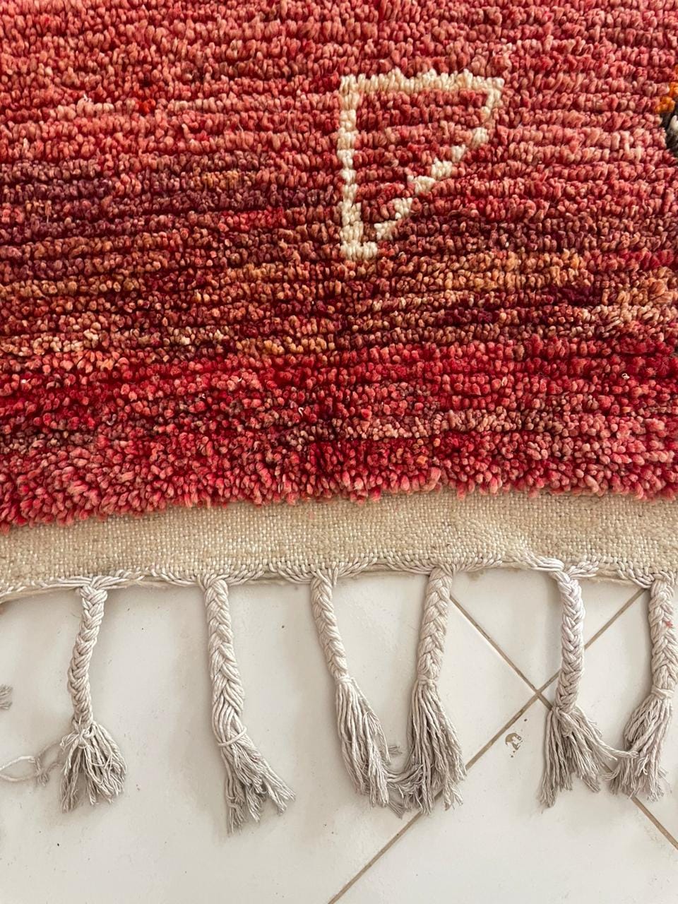 Detail shot of fringe and textured patterns on the red Moroccan rug.