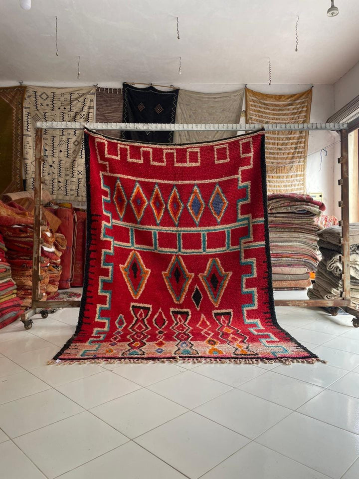 Lifestyle shot of a colorful Moroccan rug featuring geometric patterns and fringe edges.