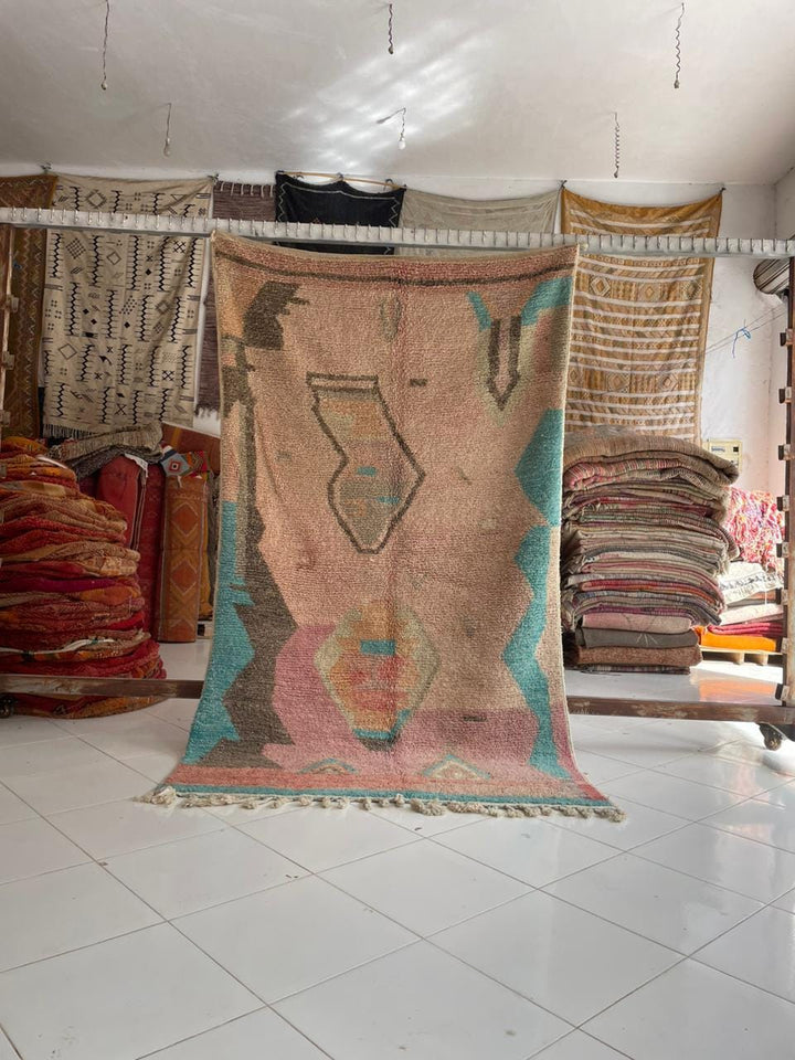 Lifestyle shot of a colorful Moroccan rug featuring tribal patterns and fringe edges.