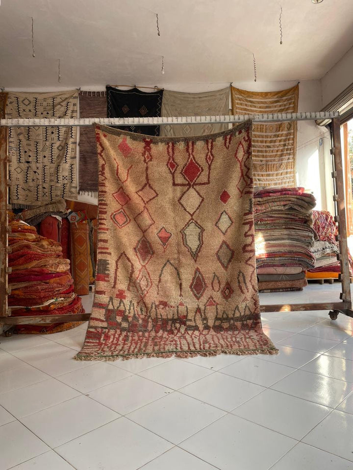 Lifestyle shot of a colorful Moroccan rug featuring red, beige, and brown tones.