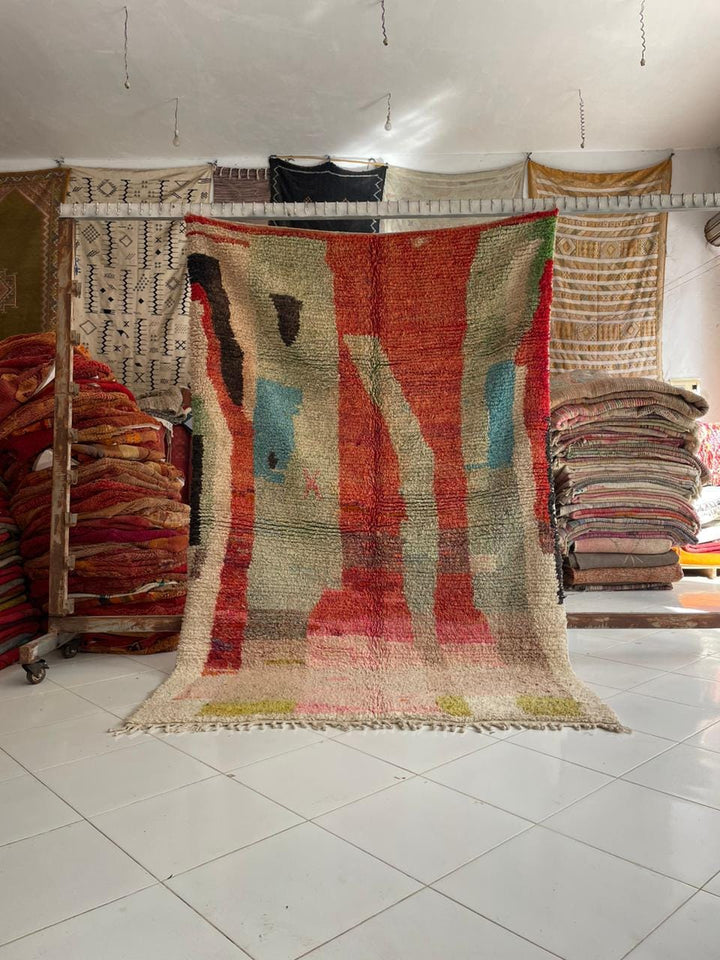 Lifestyle shot of a colorful Moroccan rug with fringe edges in a natural setting.