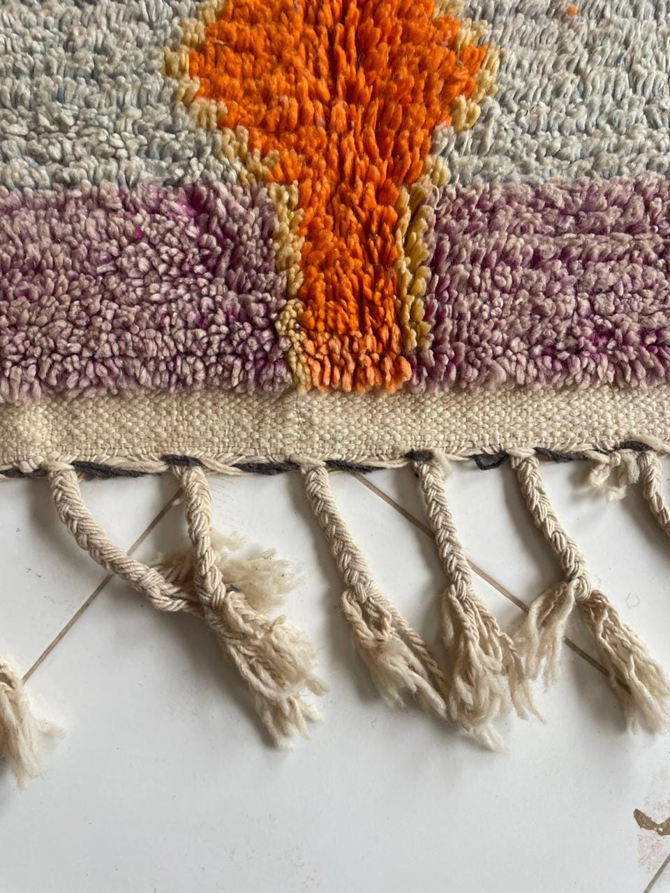 Detail shot of a colorful rug featuring fringe detail and a textured pattern.