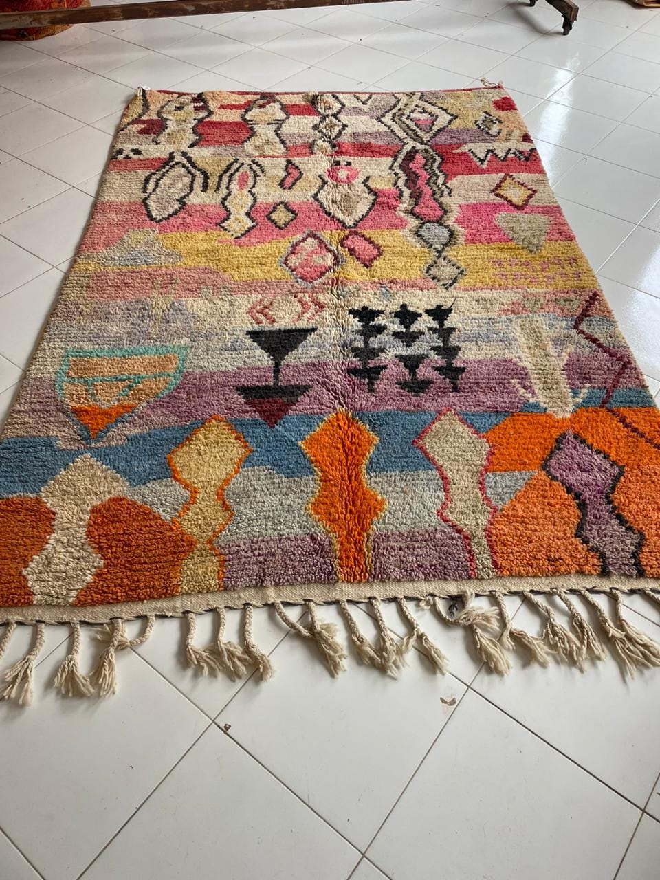 Lifestyle shot of a colorful rug featuring fringe edges and geometric designs.
