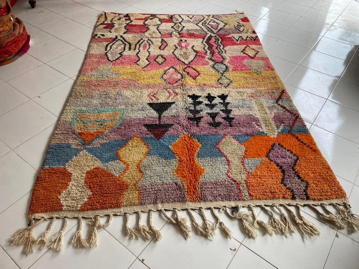 Detail view of a colorful Moroccan rug featuring geometric designs and fringe edges.