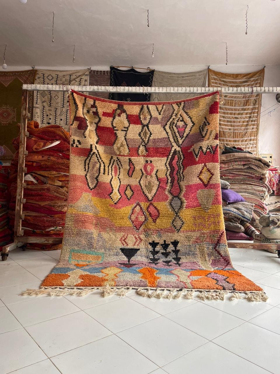 Lifestyle shot of a colorful Moroccan rug with intricate patterns and fringe edges.