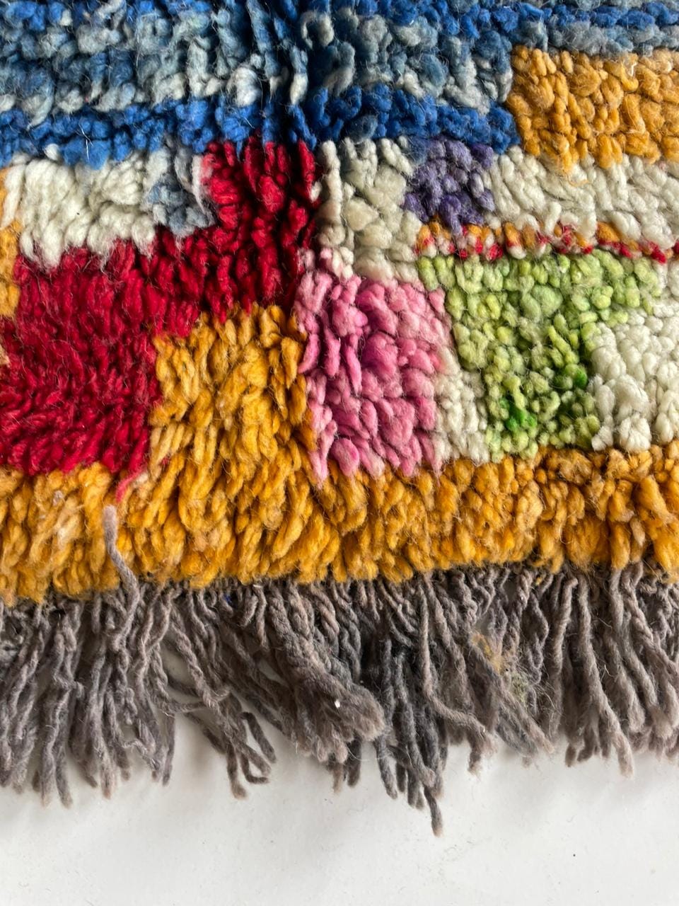 Close-up detail of a colorful Moroccan rug featuring fringe edges and vibrant colors.