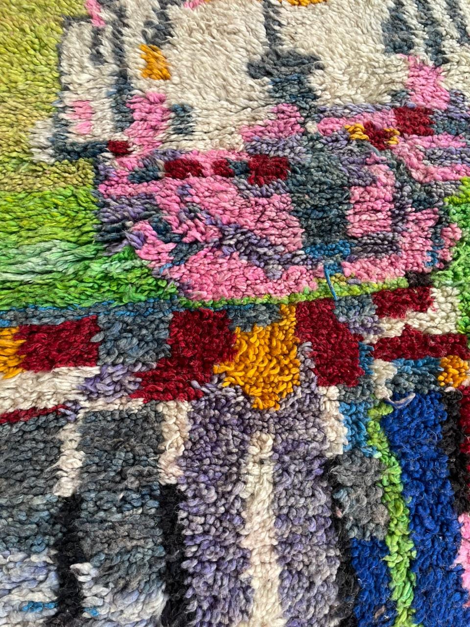 Close-up detail of a colorful Moroccan rug featuring a textured surface and abstract patterns.